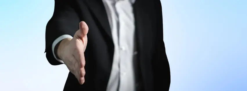 Suited man extending his hand for a handshake.